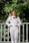woman in white dress shirt and white pants standing near white wooden fence during daytime