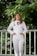 woman in white dress shirt and white pants standing near white wooden fence during daytime