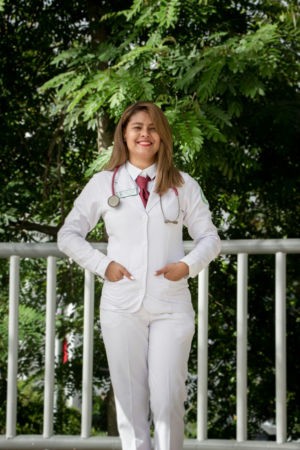 woman in white dress shirt and white pants standing near white wooden fence during daytime