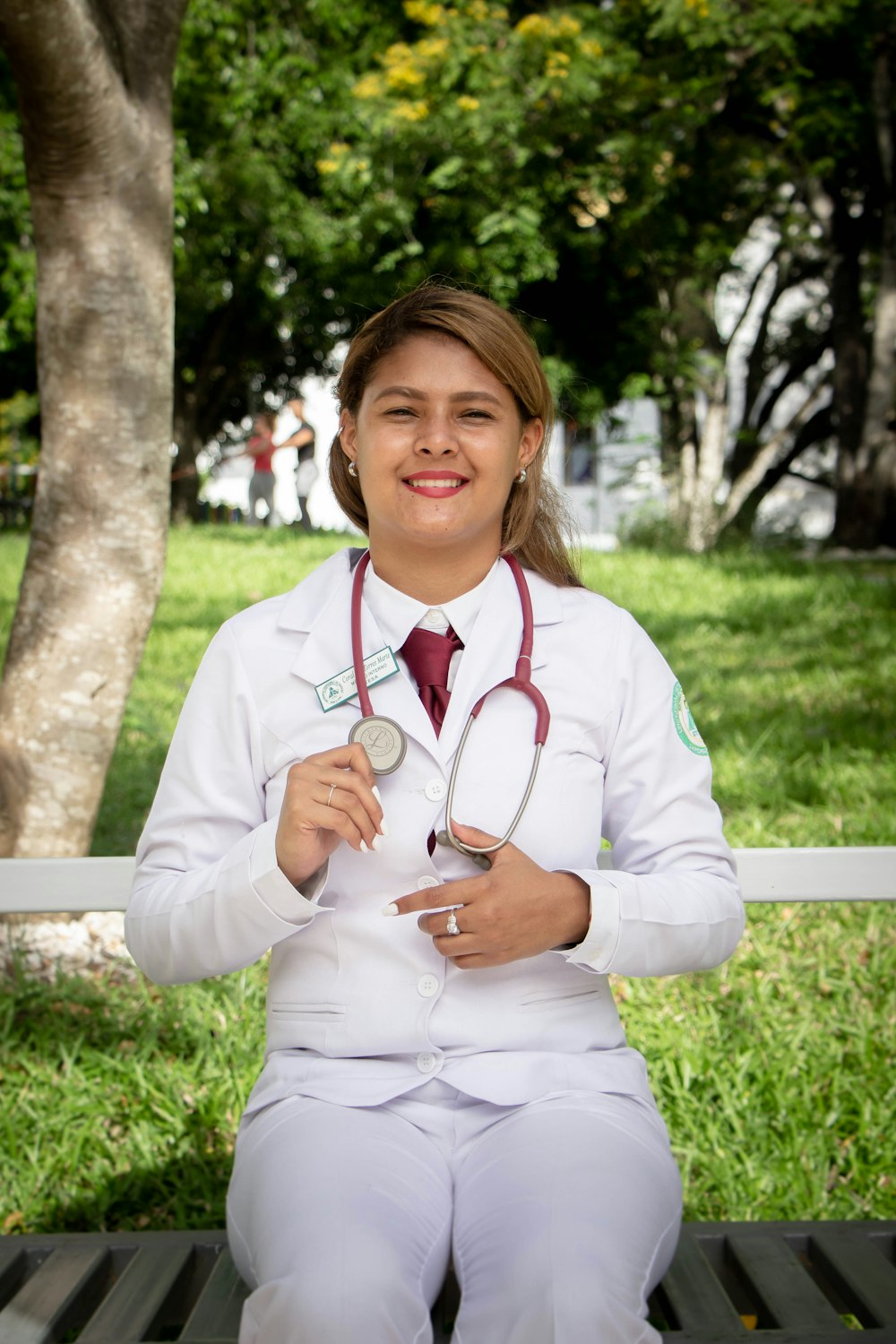smiling woman in white long sleeve shirt with stethoscope on her neck