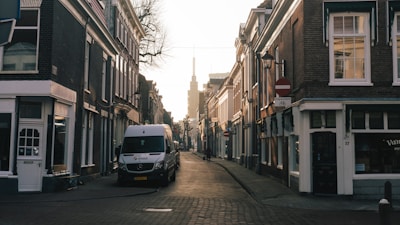 A wide shot of the van parked beside a quiet European village street lined with stone houses.