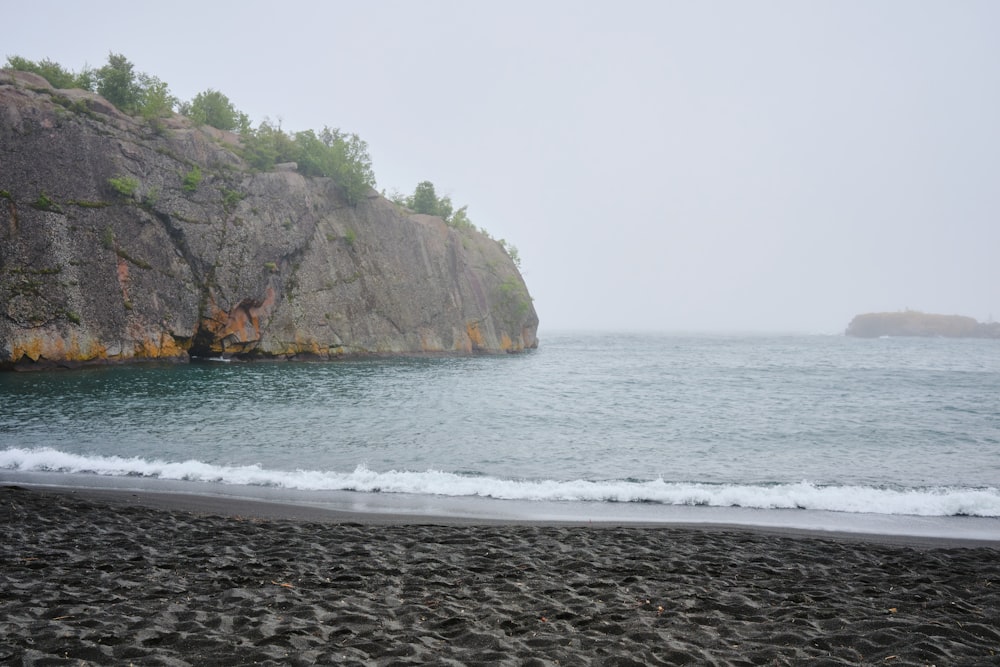 green and brown mountain beside sea during daytime