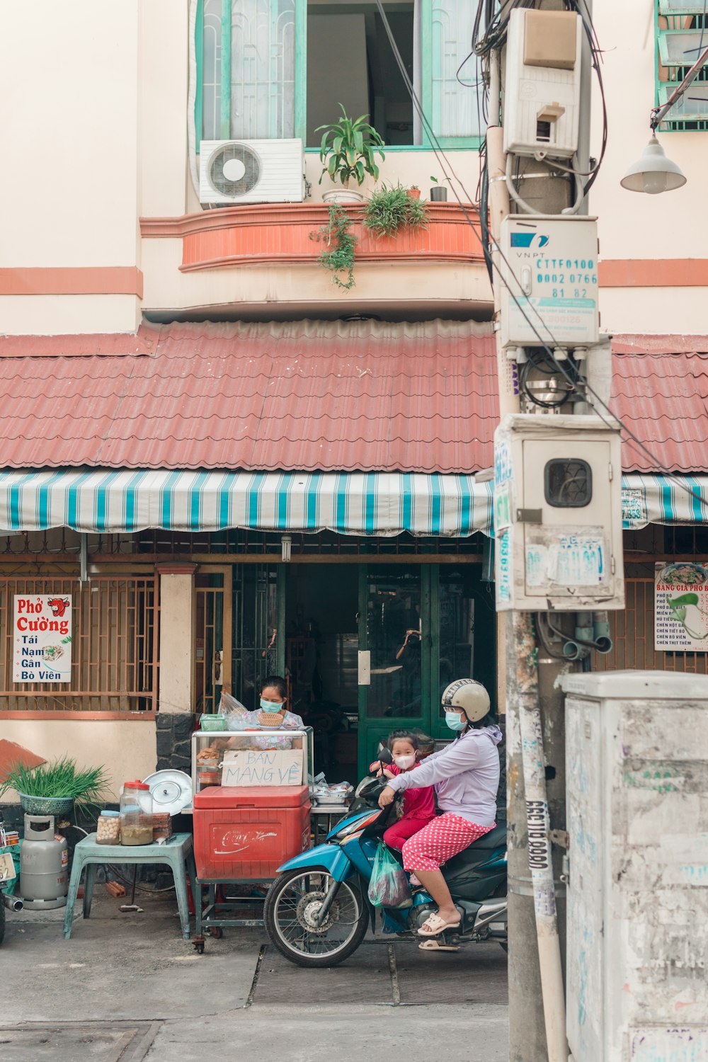 man in red shirt sitting on red bench near store during daytime