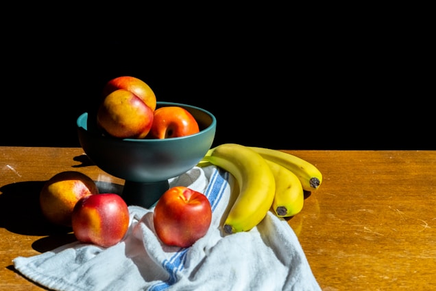 A bright, colorful arrangement of ripe mangoes and bananas on a rustic wooden table.