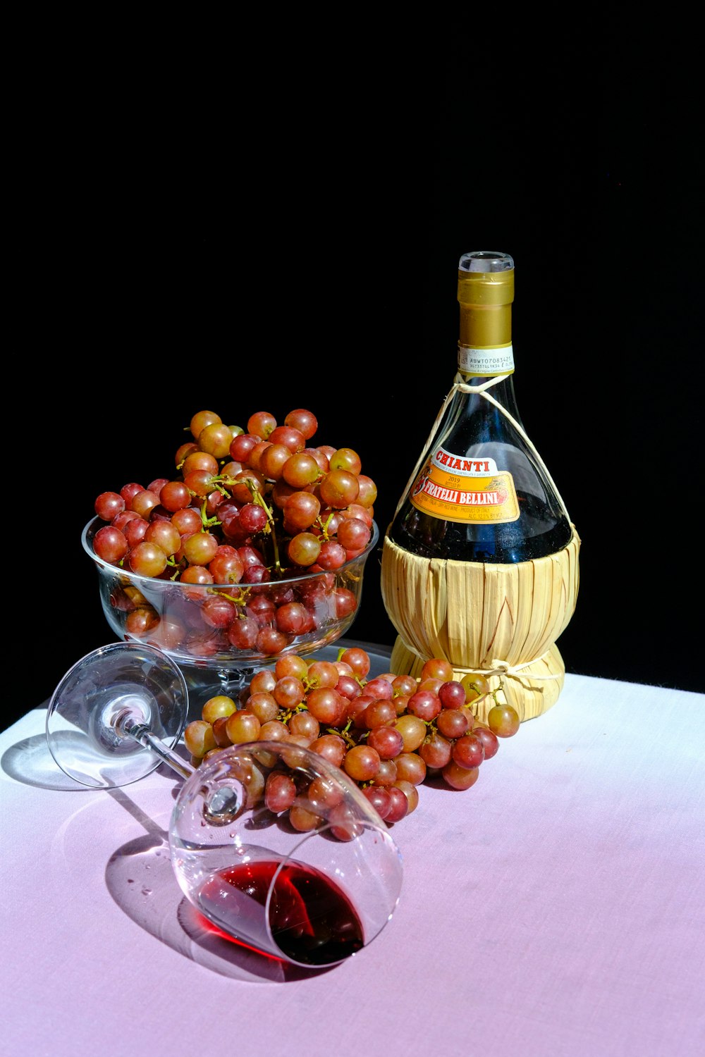 red grapes on clear glass bowl beside brown bottle