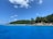 A scenic view of Okinawa's coastline with clear blue waters and lush greenery in the background.
