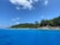 A scenic view of Okinawa's coastline with clear blue waters and lush greenery in the background.