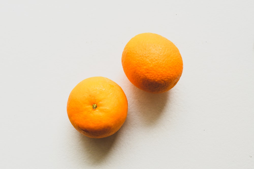 2 fruits orange sur table blanche