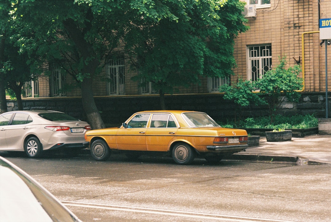 yellow sedan on road near green trees during daytime