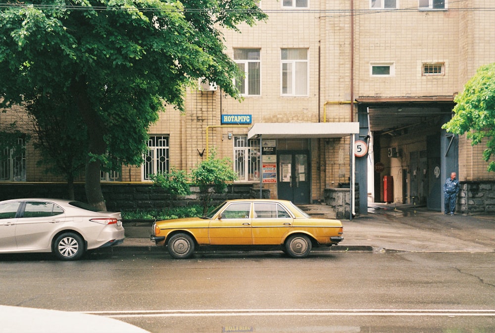 yellow sedan on road near green trees and building during daytime