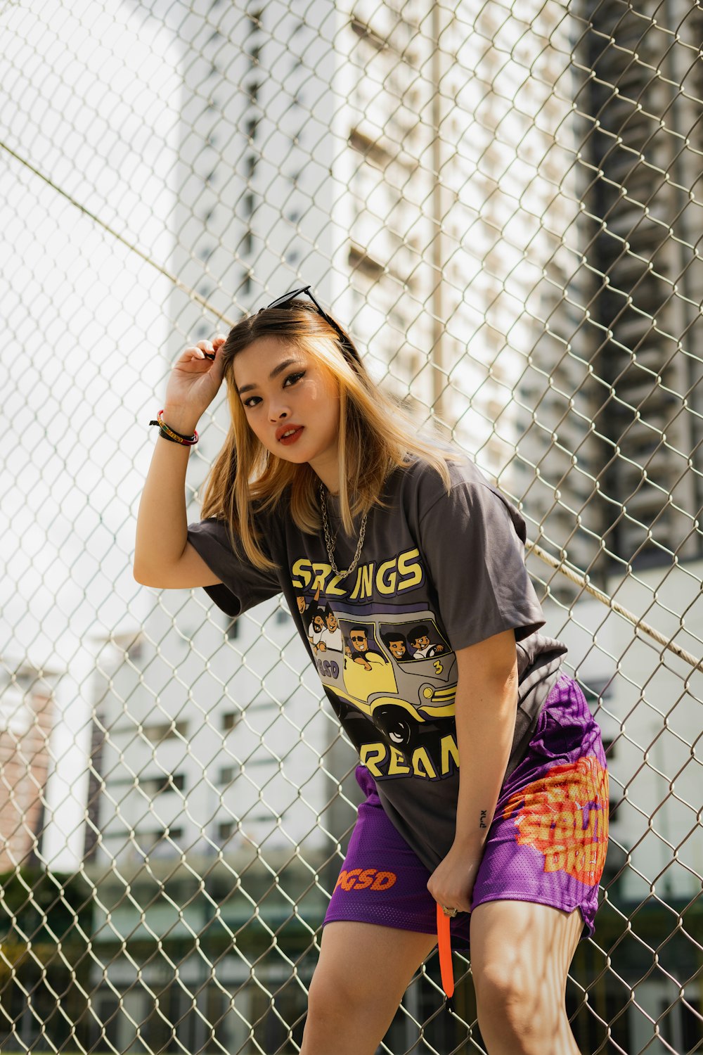 woman in black and yellow crew neck t-shirt standing beside gray metal fence during daytime