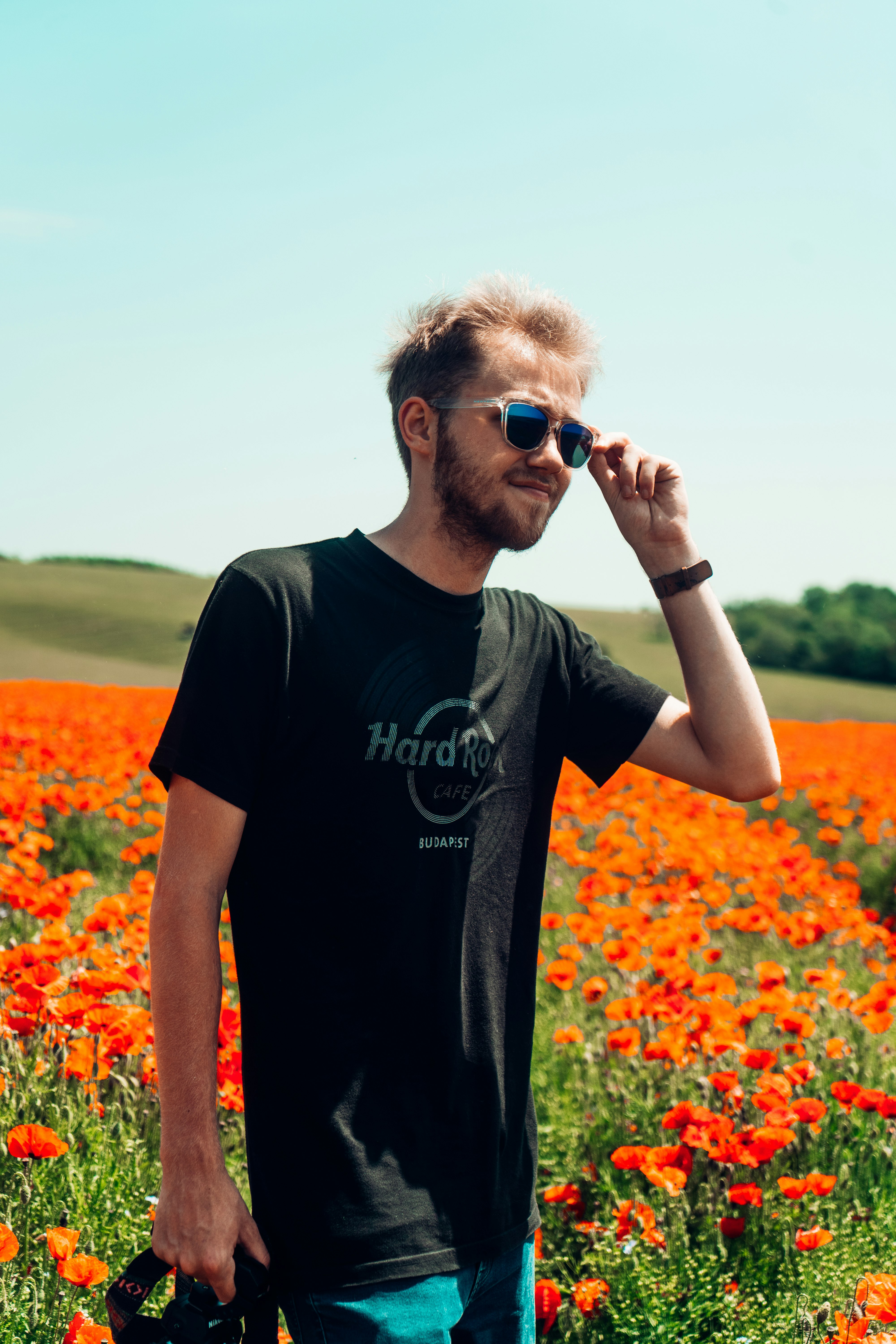 man in black crew neck t-shirt wearing black sunglasses standing on flower field during daytime