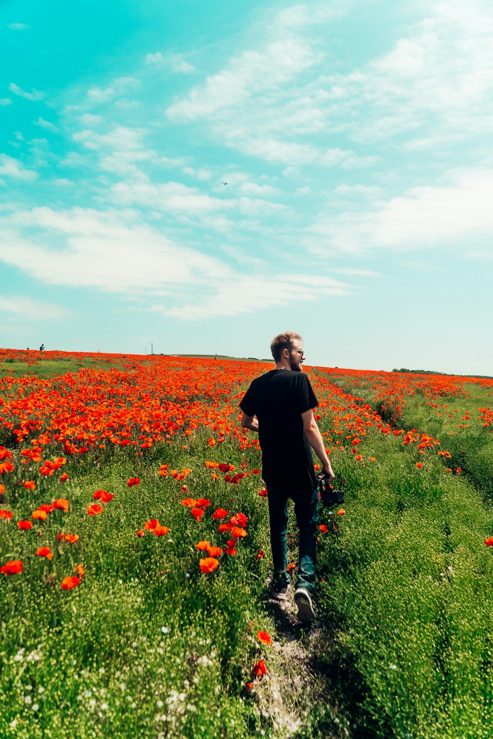 man in black long sleeve shirt and black pants walking on green grass field during daytime