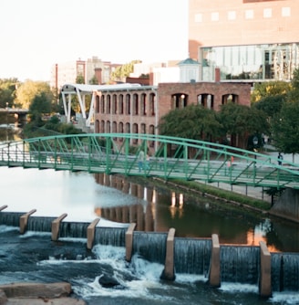 water falls near green bridge during daytime