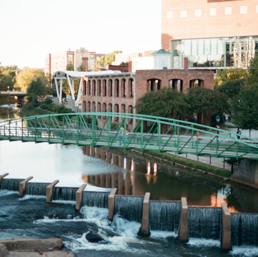 water falls near green bridge during daytime