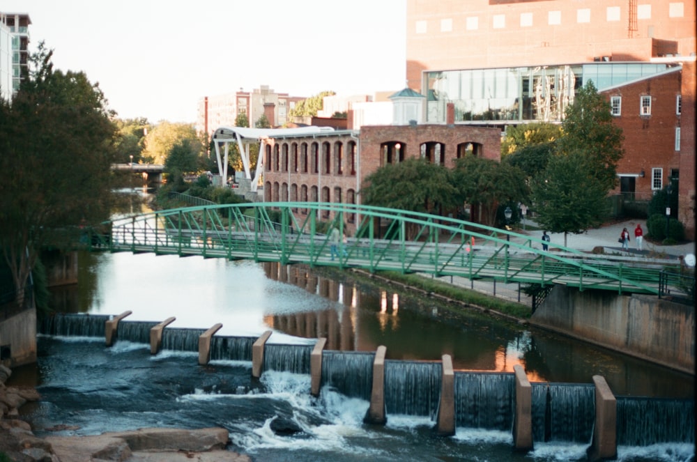 water falls near green bridge during daytime