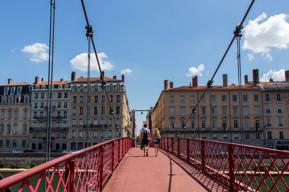 people walking on red bridge near brown concrete building during daytime