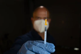 white and clear syringe on blue textile