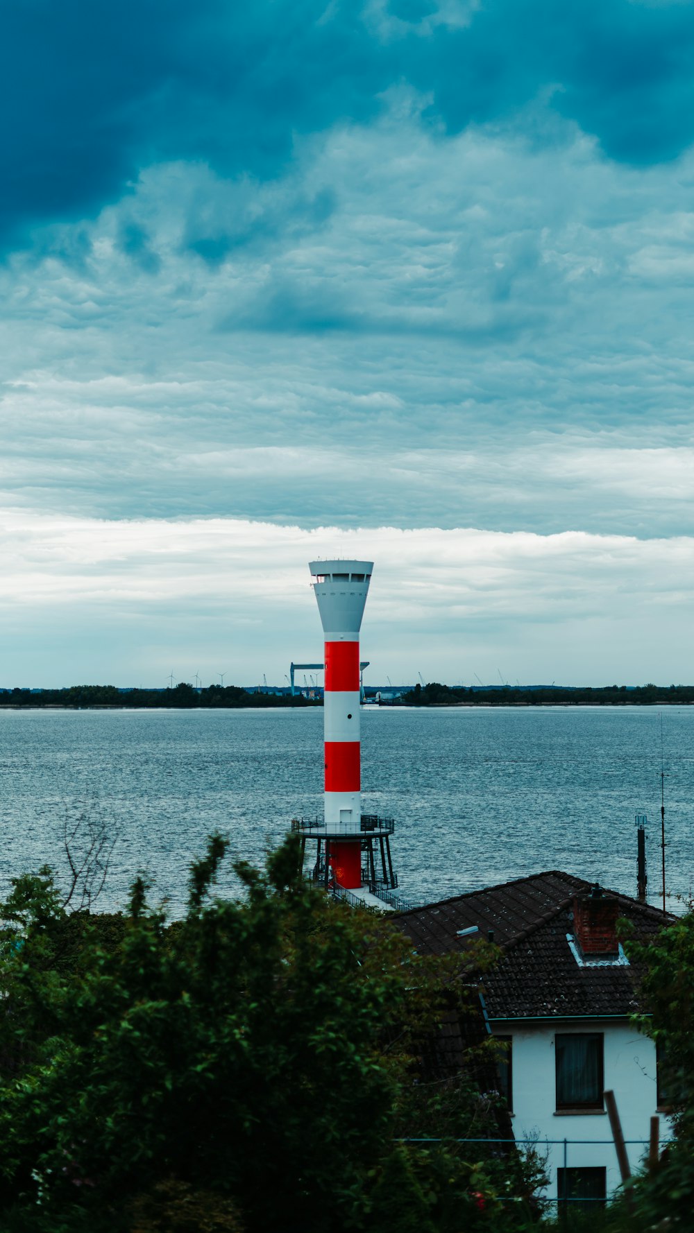 white and red lighthouse near body of water under cloudy sky during daytime