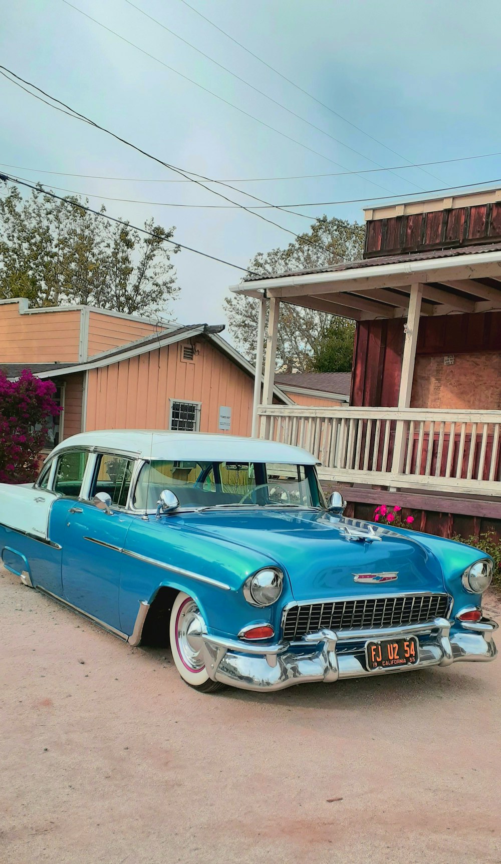 blue vintage car parked beside brown wooden house during daytime