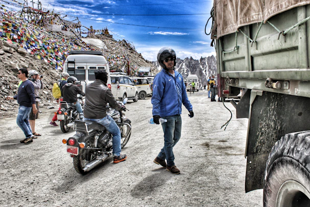 Motor-and-trek hybrid group crossing a high mountain pass in Ladakh with rugged vehicles.