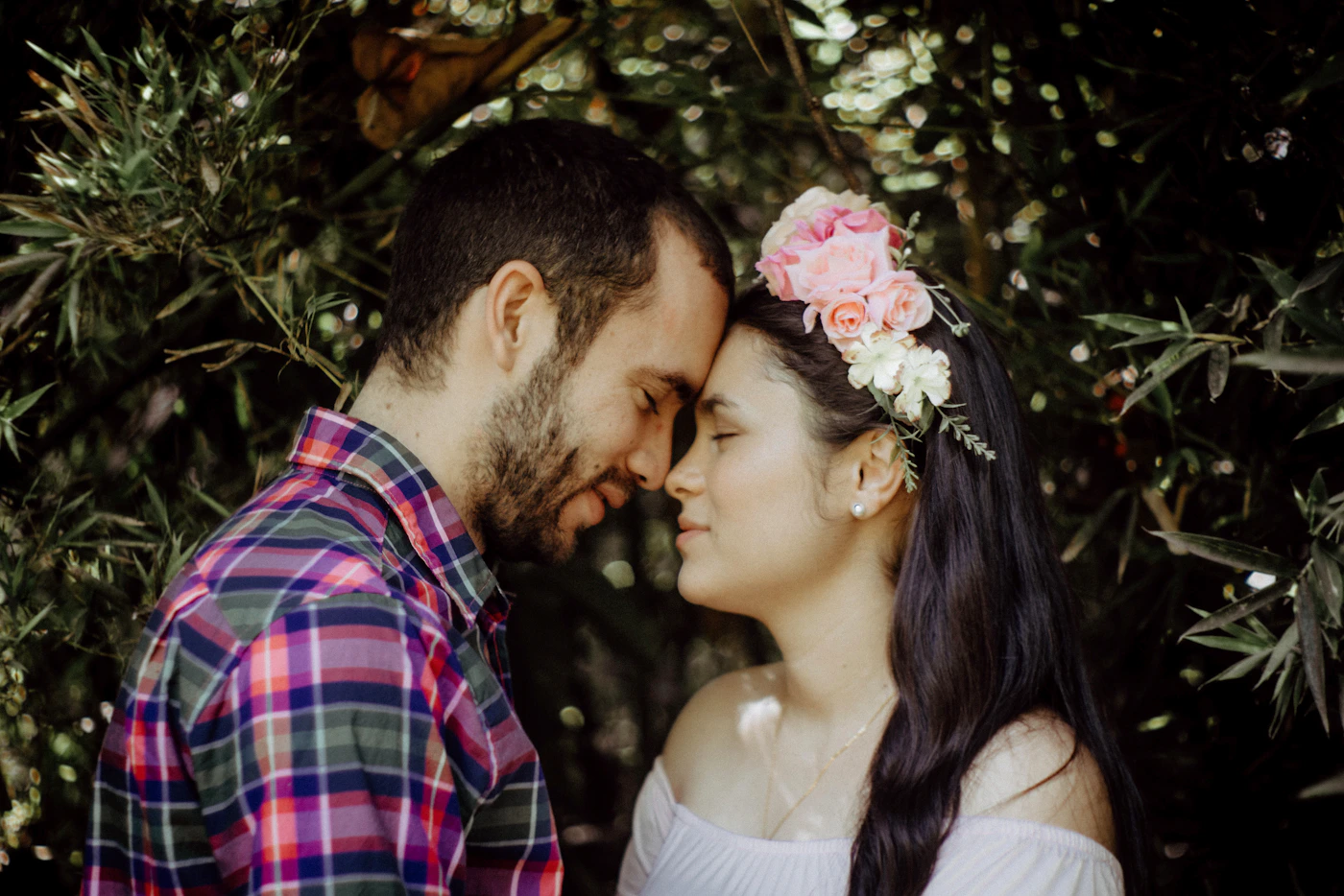 A romantic couple with the woman wearing a flower crown in a lush tropical garden in Colombia with soft bokeh background light