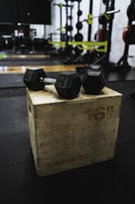 black and gray dumbbells on brown wooden crate