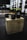 A gym setting with two black hexagonal dumbbells placed on a wooden plyometric box. In the background, there are various pieces of workout equipment including weight racks and bars. The scene appears focused and organized.