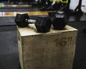 black and gray dumbbells on brown wooden crate