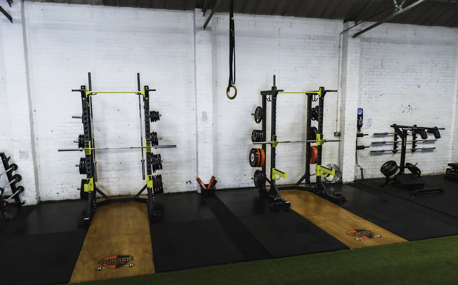 A squat rack with a loaded barbell in a dim training space
