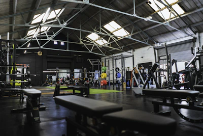 Weightlifting equipment and benches in a spacious industrial gym with a high ceiling