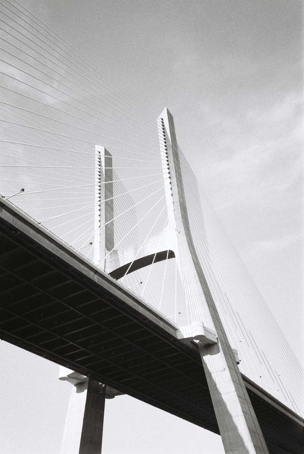 grayscale photo of bridge under cloudy sky