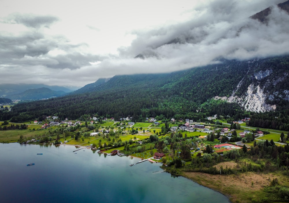 houses near lake and mountain under white clouds during daytime