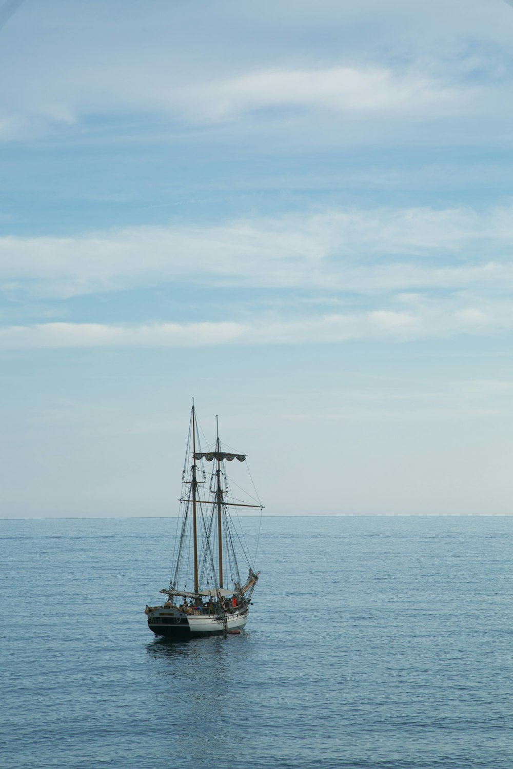 brown sail boat on sea under white clouds during daytime