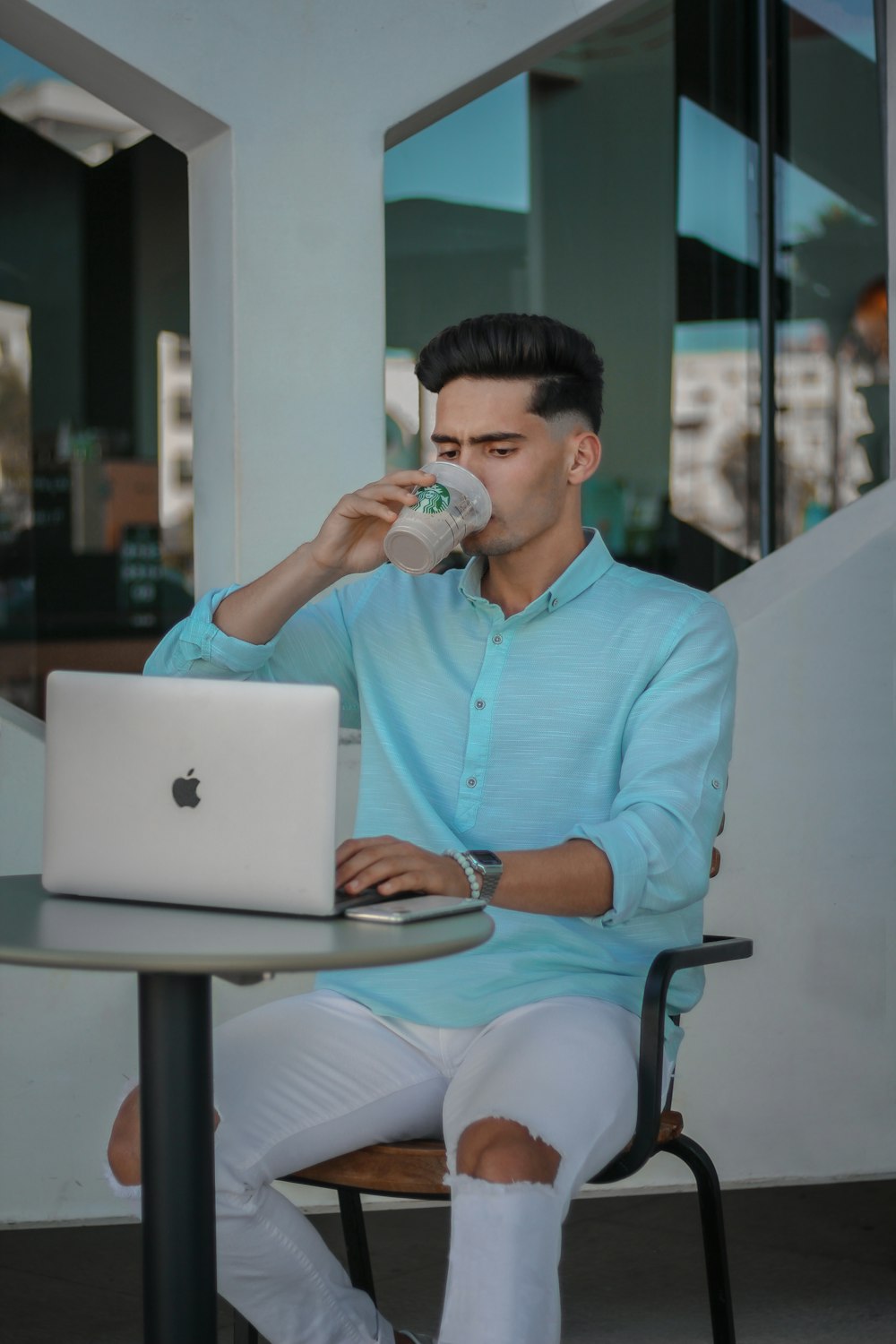 woman in blue dress shirt sitting on chair while using macbook