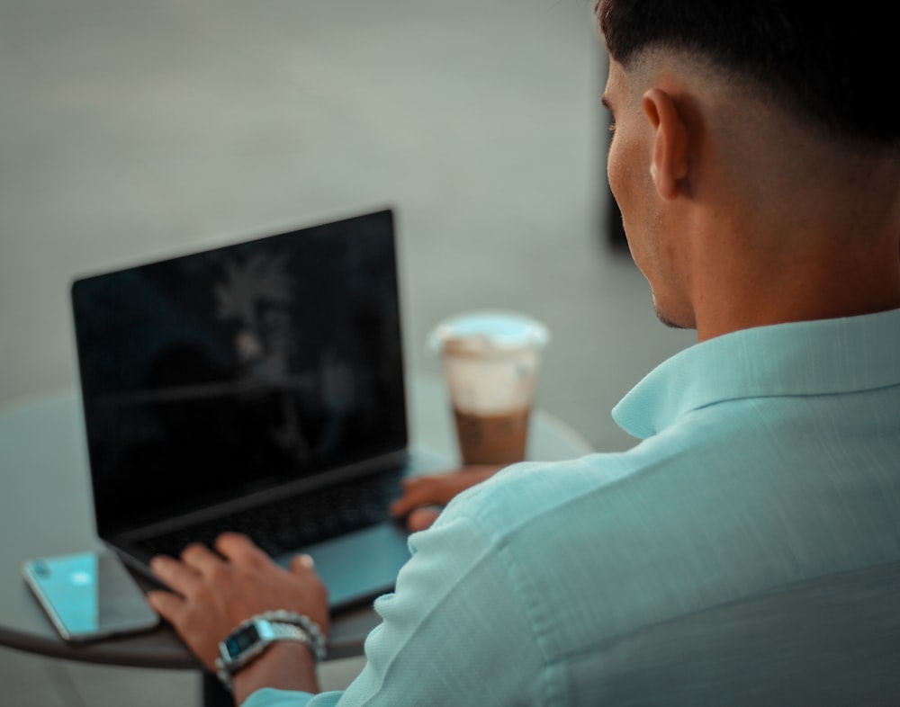 man in blue polo shirt using black laptop computer