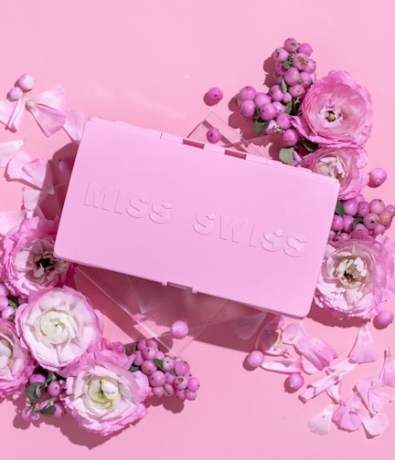A pastel pink surprise box with the Blossom Box logo, surrounded by cute collectible figurines peeking out.