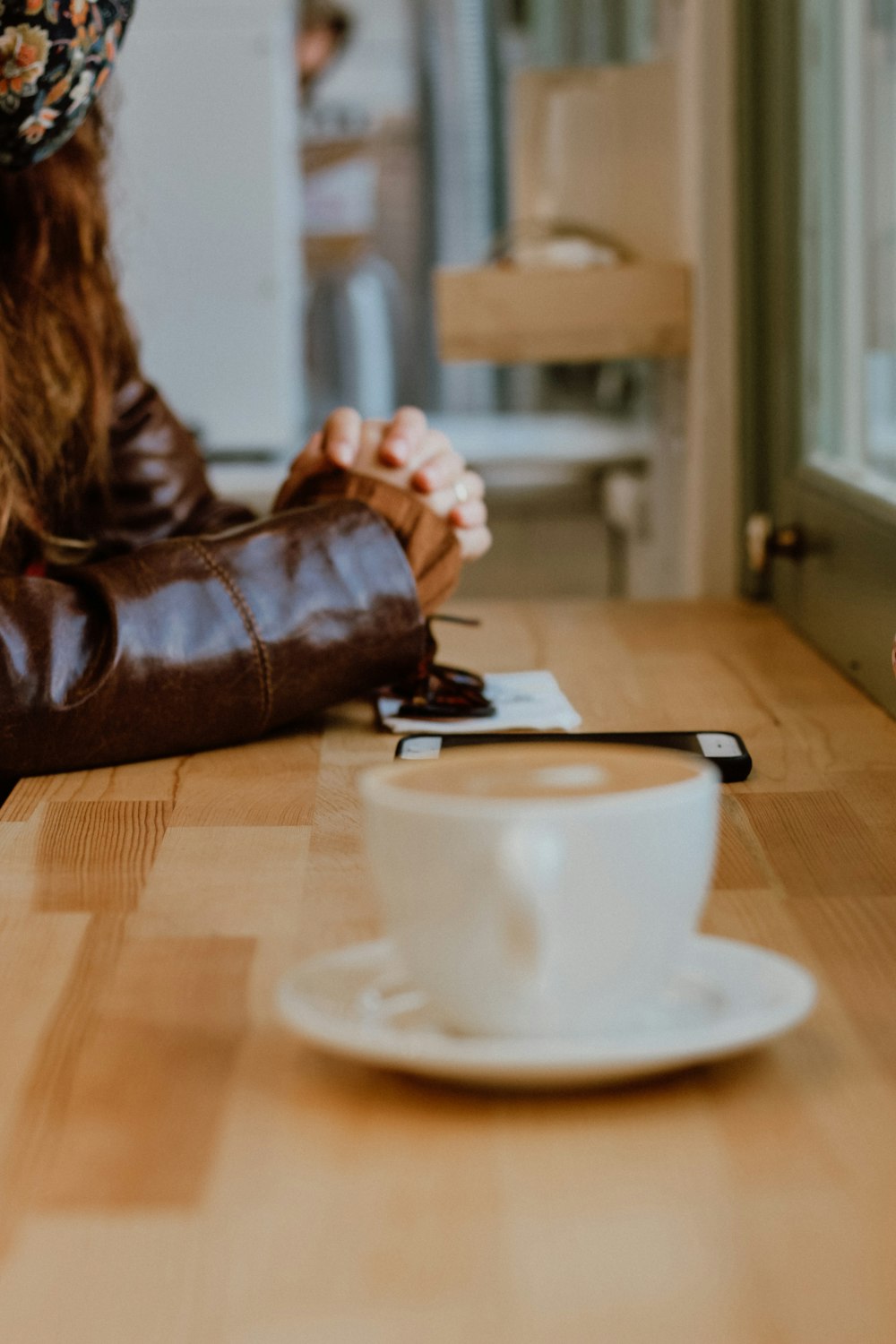 woman in brown leather jacket holding black smartphone on brown leather couch