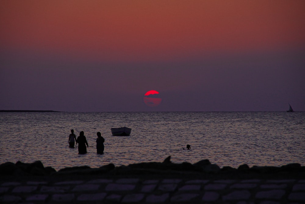 Silhouette von Menschen am Strand während des Sonnenuntergangs