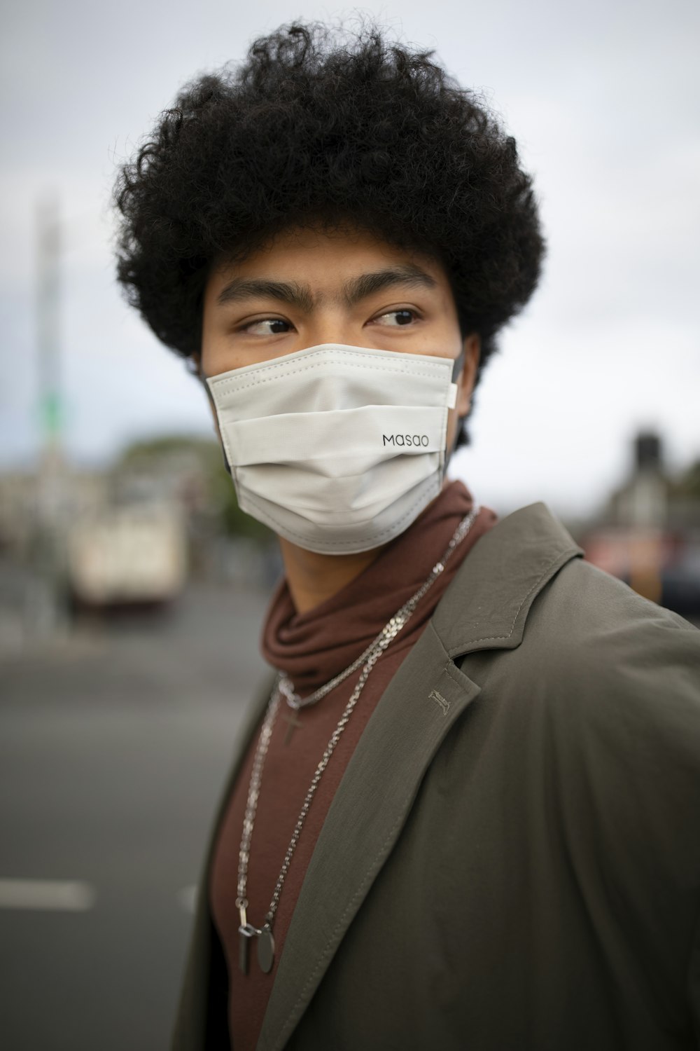 woman in brown coat wearing white face mask