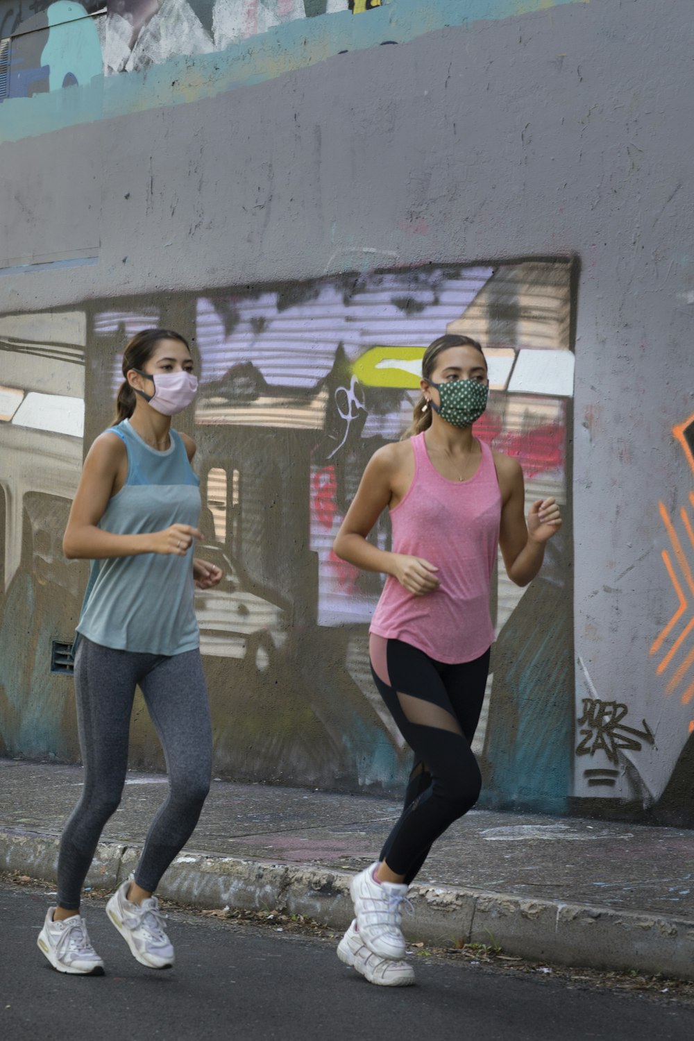 woman in pink tank top and gray leggings standing beside woman in gray tank top