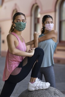 woman in pink tank top and blue denim jeans wearing black mask