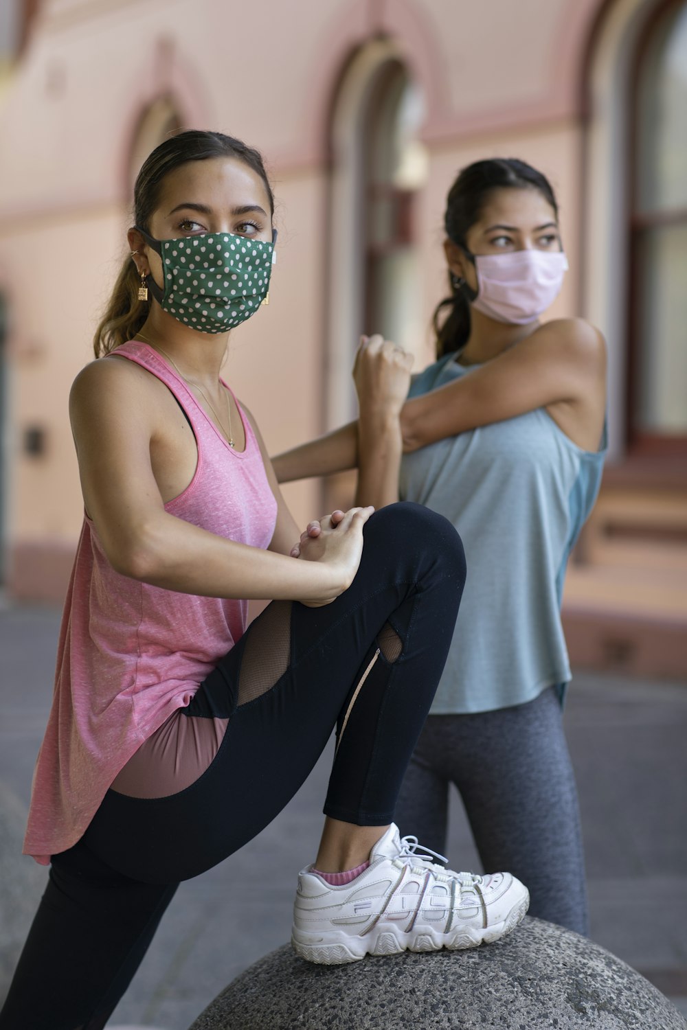 woman in pink tank top and blue denim jeans wearing black mask