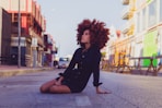 woman in black long sleeve shirt sitting on sidewalk during daytime