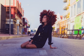 woman in black long sleeve shirt sitting on sidewalk during daytime