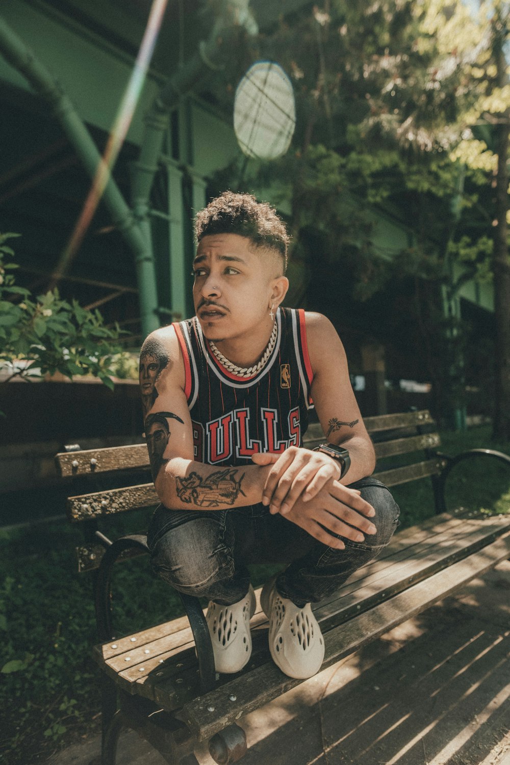 man in red and white tank top sitting on brown wooden bench