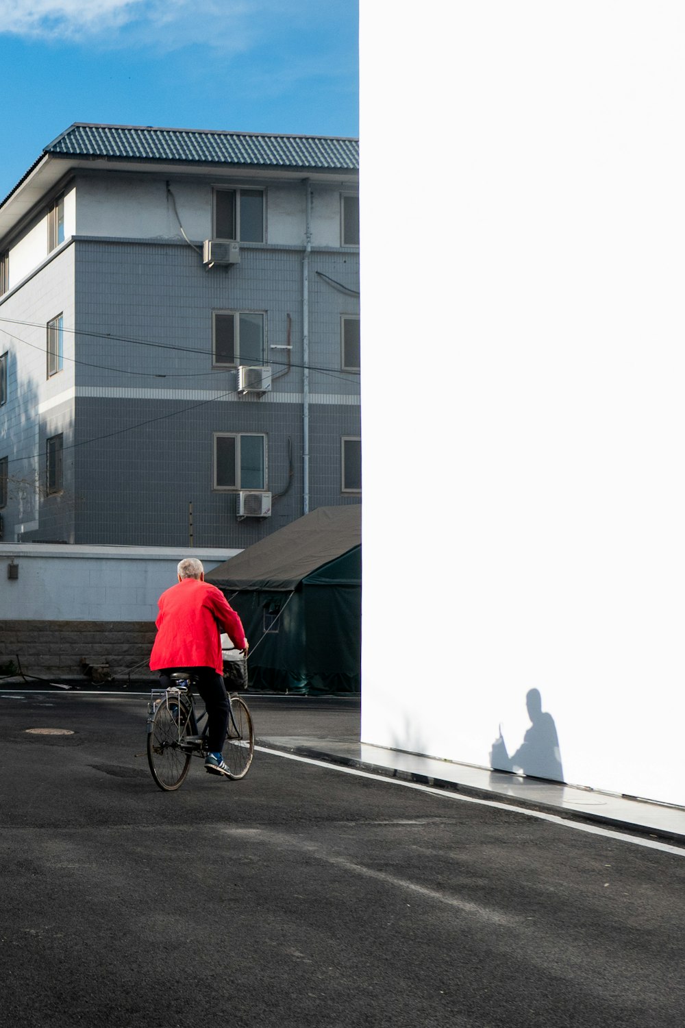 homem no capuz vermelho que anda de bicicleta na estrada durante o dia