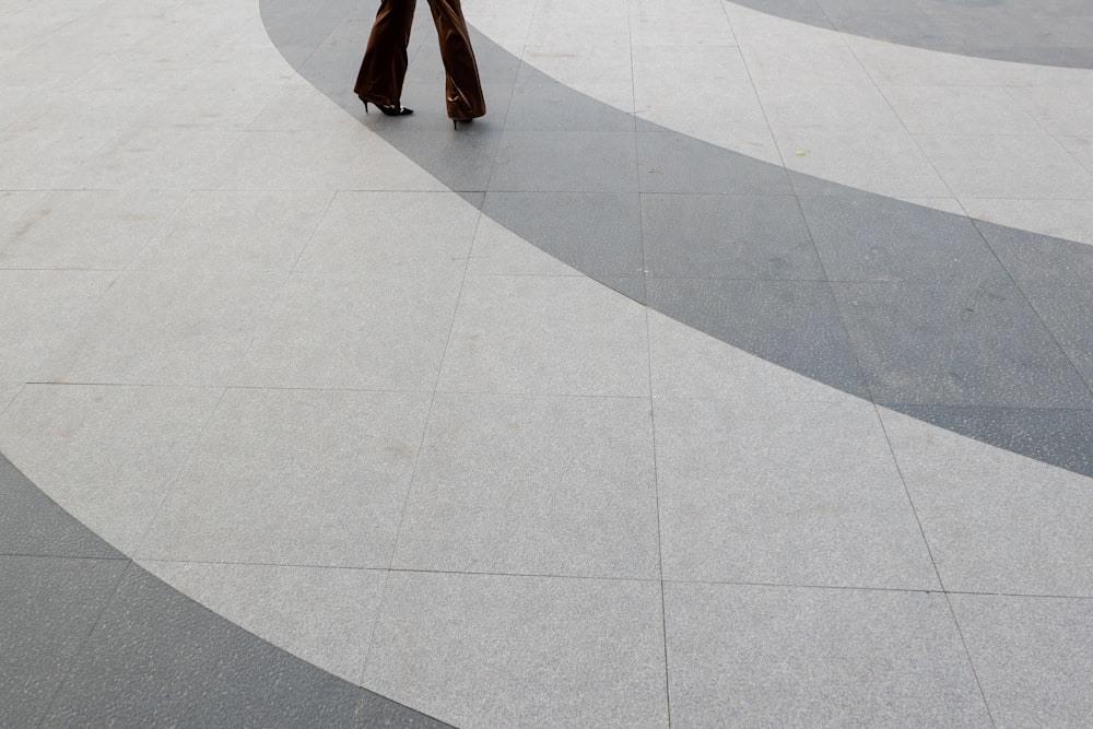 person in brown pants walking on gray concrete pavement