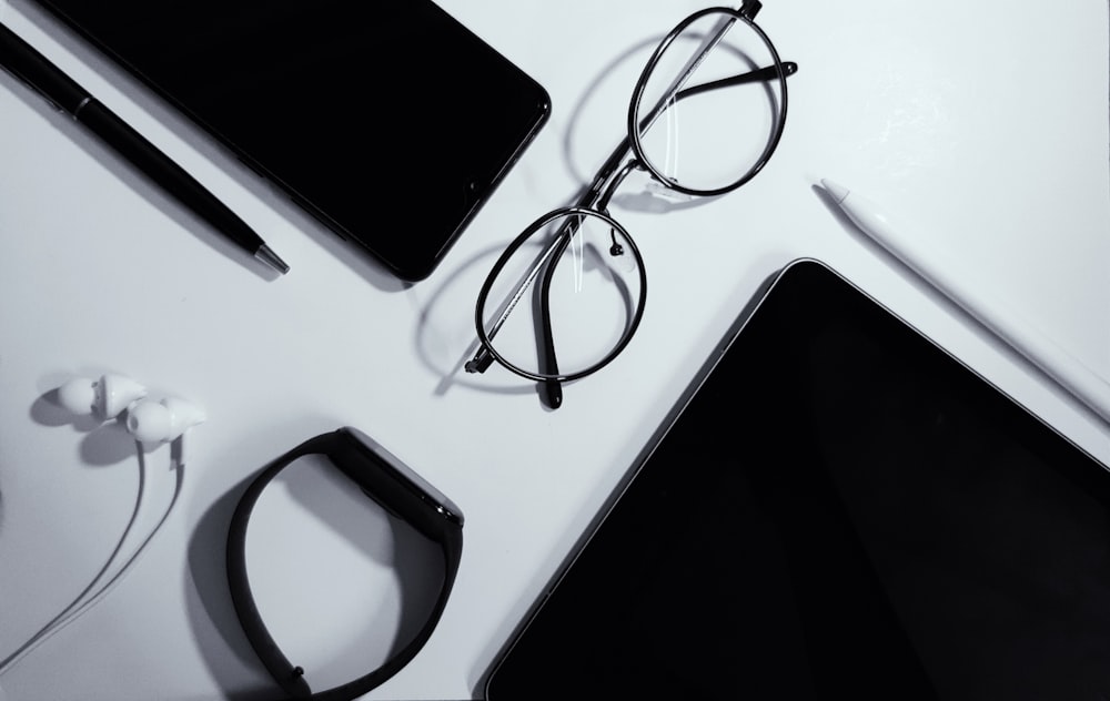 black ipad beside black framed eyeglasses
