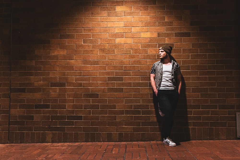 woman in black and white striped shirt and black pants standing beside brown brick wall